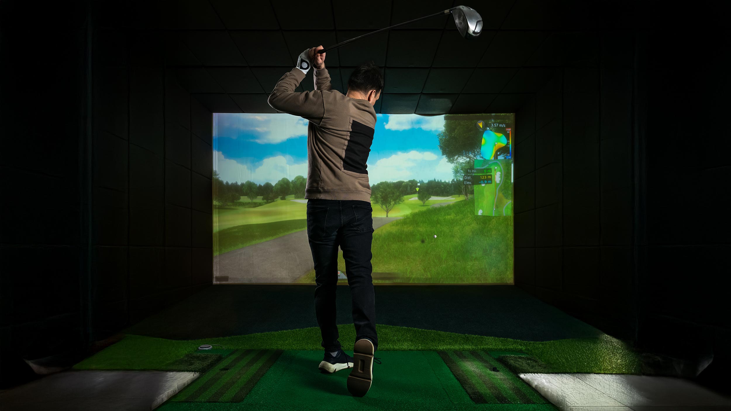 Man using a high-tech indoor golf simulator with performance analytics