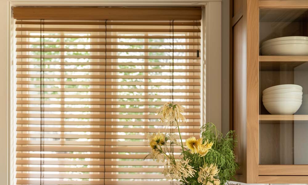 Kitchen window with wooden horizontal blinds and floral decor