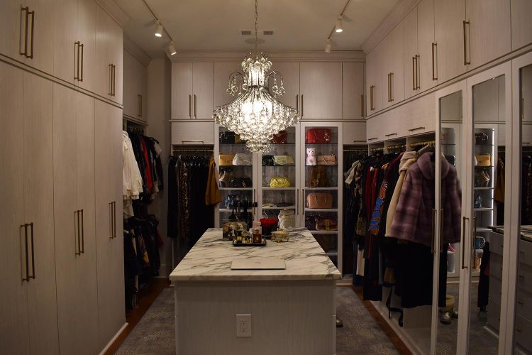 Spacious walk-in closet with marble island and glass chandelier