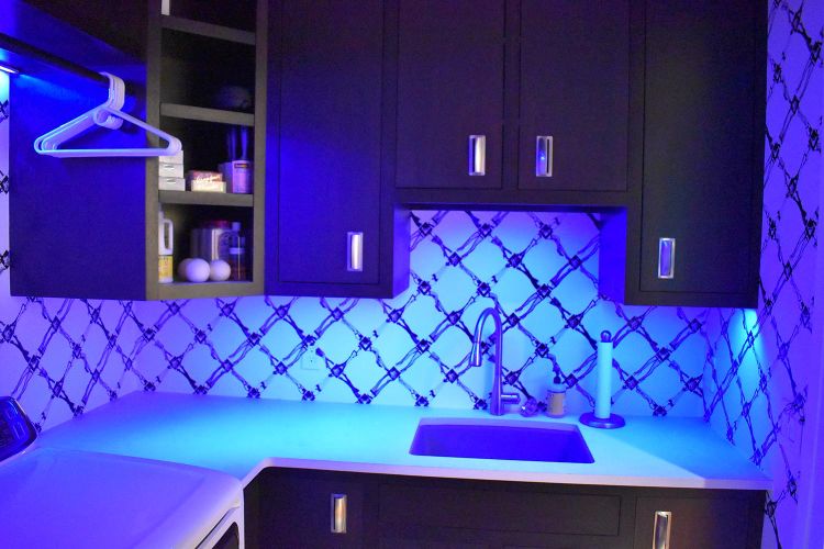 Laundry room with blue LED lighting, patterned backsplash, and dark cabinetry