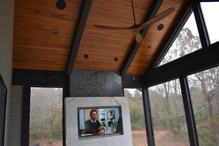 Vaulted wooden ceiling above outdoor lounge space with wall-mounted TV