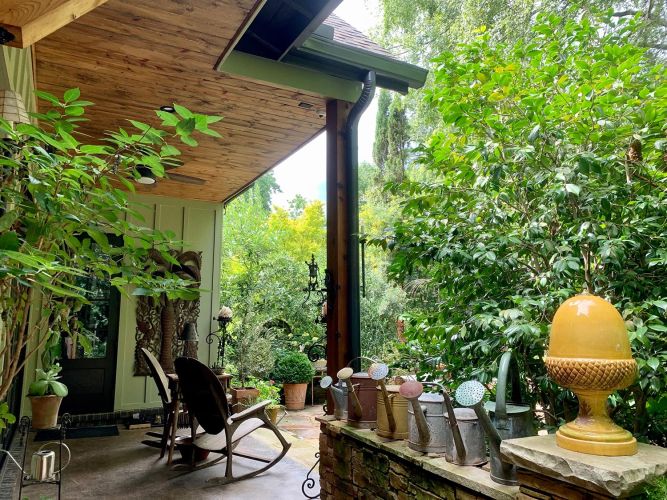 Porch with potted plants, gravel path, and a small decorative stained window
