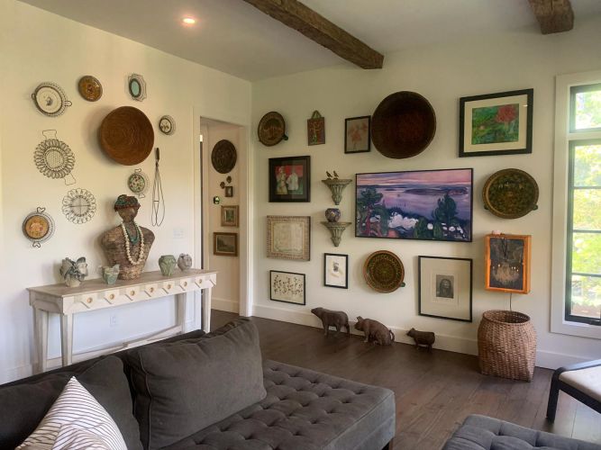 Art-filled living room wall with eclectic decor and gray tufted seating