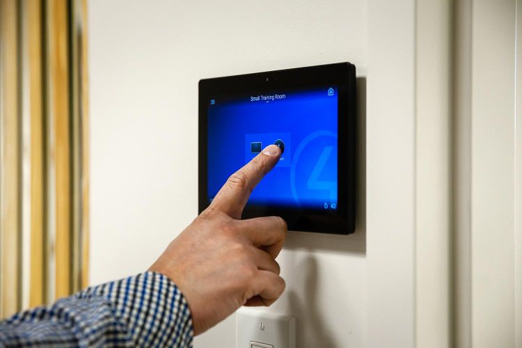 Person using touch screen panel on wall to control room functions
