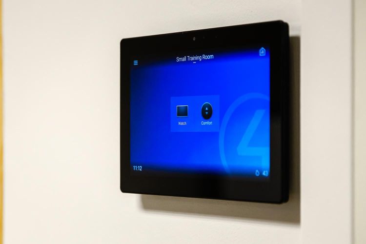 Wall-mounted touch control panel displaying training room interface