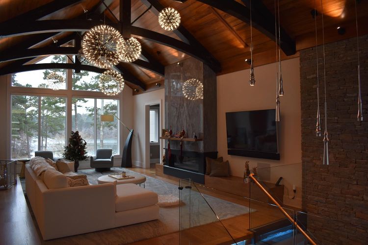 Open living space with dark ceiling beams and floor-to-ceiling windows overlooking a lake