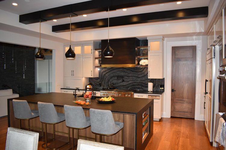 Stylish kitchen with black island and ceiling beams, warmly lit