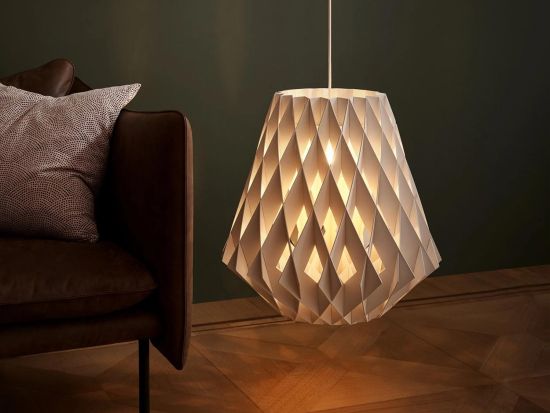 Ketra Pilke lighting fixture with warm, low lighting in a room with a brown chair and dark green walls.