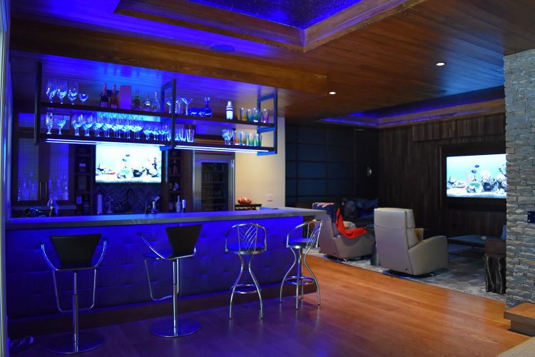 Lounge and bar area with blue accent lighting and wall-mounted fish tank