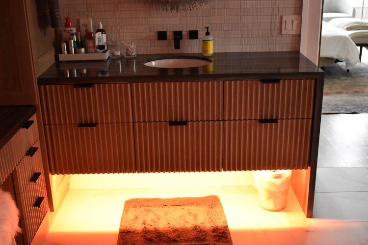 Bathroom vanity with ribbed wood texture and orange under-cabinet lighting