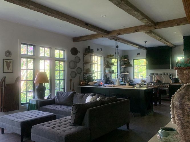 Open-plan kitchen and living room with natural light and wooden ceiling beams